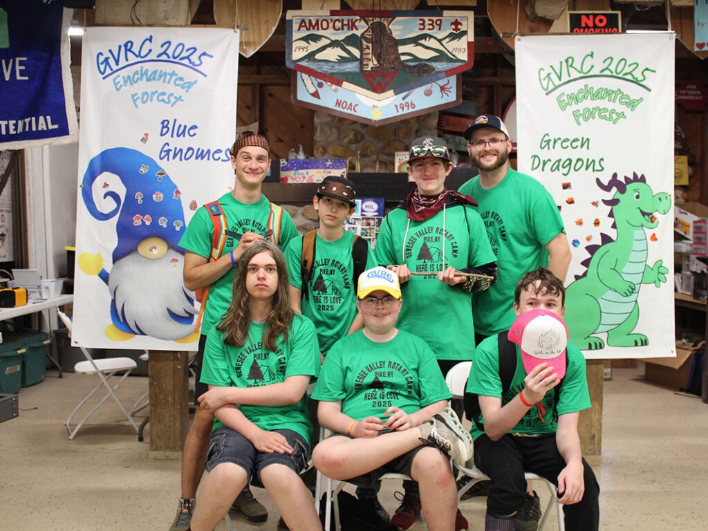 Group posing at 2025 camp with banners.