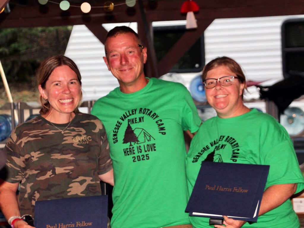 Three people smiling at Rotary Camp event.