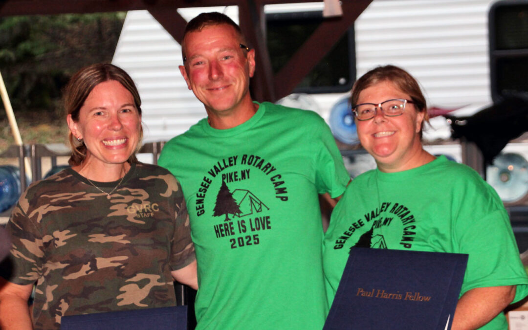 Three people smiling at Rotary Camp event.