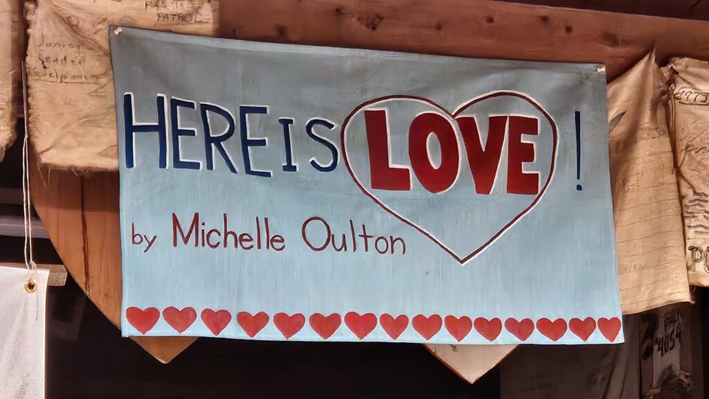 Sign reading 'Here is Love' with hearts.
