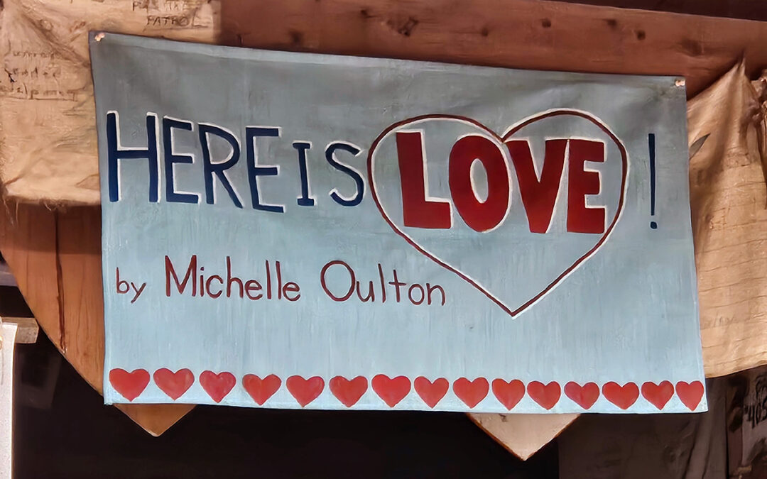 Sign reading 'Here is Love' with hearts.