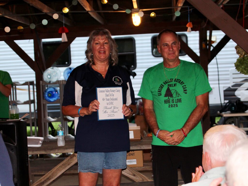 Two people receive appreciation plaque at event.
