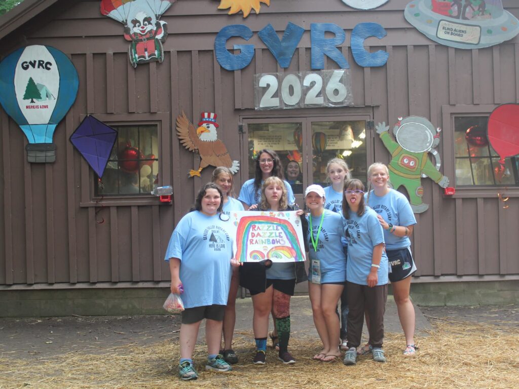 Camp group holds rainbow sign outside decorated GYRC building