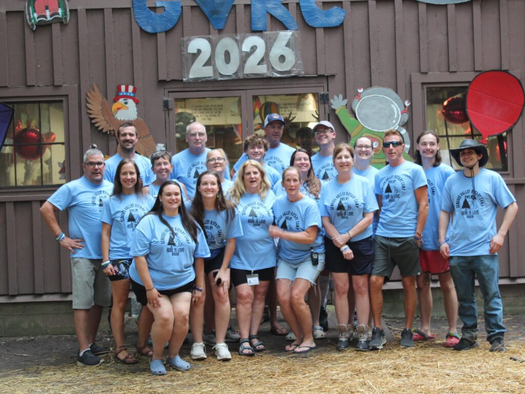 Group wearing matching shirts poses outside a camp building