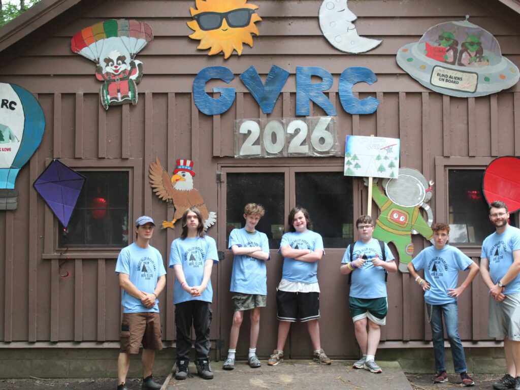 Seven campers pose beneath colorful GYRC 2026 cabin decorations.