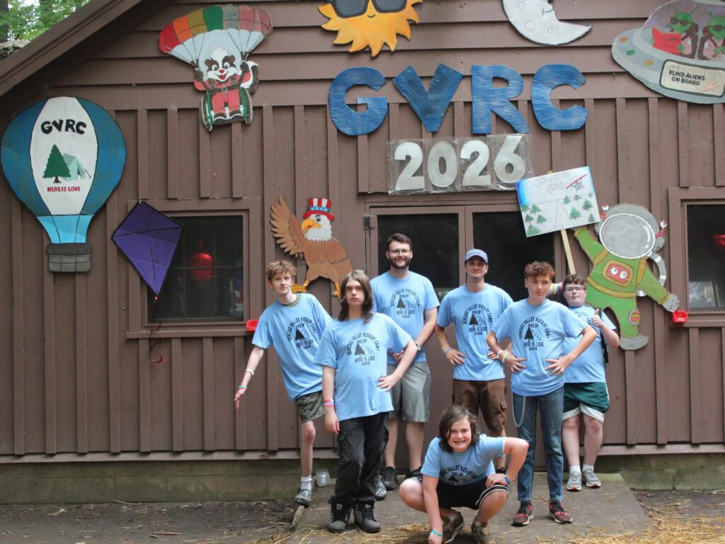 Youth group poses before decorated 2026 camp cabin.