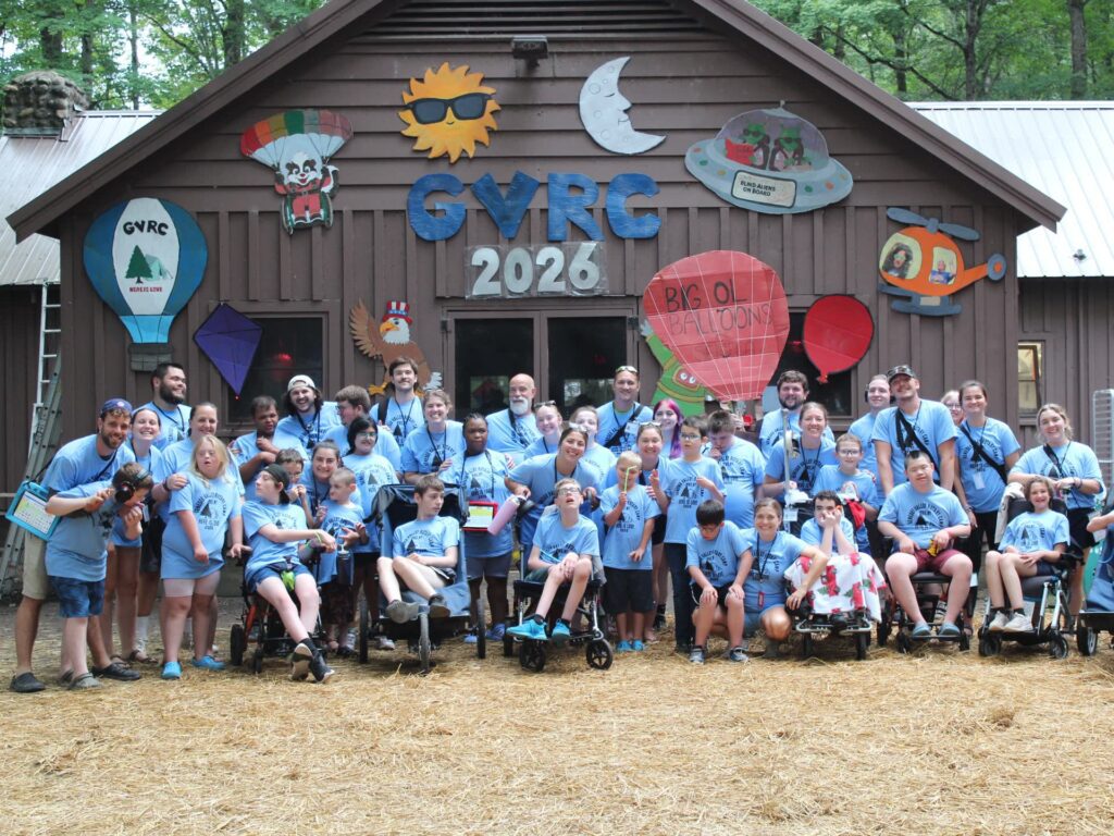 Group in blue shirts poses beneath GVRC 2026 camp decorations